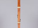 a wooden flute on a clear stand with a white background