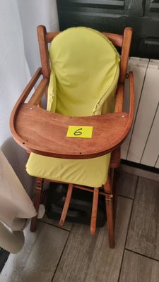 une chaise haute en bois avec un siège jaune, placée devant une porte
