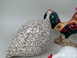 two ceramic figurines of roosters standing next to each other