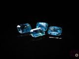 three pieces of blue topazte sit on a black surface