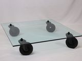 une table basse en verre munie de roulettes, sur fond blanc