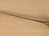 une trompette en laiton posée sur une table en bois et attachée par une ficelle