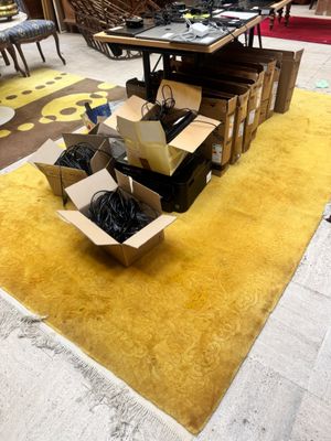 un tapis jaune posé à même le sol, sur lequel se trouvent des cartons