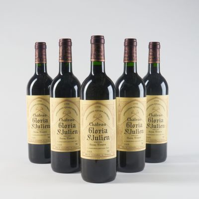 four bottles of red wine are lined up on a white surface