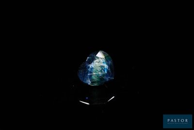 a blue and green sapphire stone on a black surface
