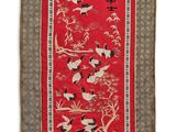 a red rug with birds and flowers on it
