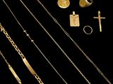 plusieurs colliers en or, des bagues et une croix sur fond noir
