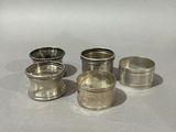 three silver napkins and a silver cup on a white surface