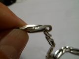 une personne tenant une chaîne en argent sur laquelle est fixée une bague