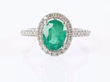 a close up of a ring with a green stone surrounded by diamonds