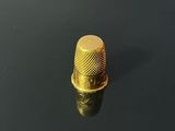 a close up of a gold thimble on a black surface