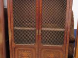une armoire en bois avec une porte vitrée, devant laquelle se trouve une chaise