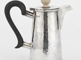 une cafetière ancienne en argent avec une poignée noire sur fond blanc