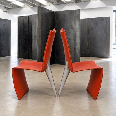 une chaise rouge qui se trouve dans une pièce aux murs en béton