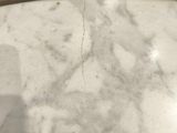a glass table with a white marble top on a wooden floor