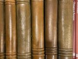 several old books are lined up on a shelf next to each other