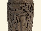 un vase marron orné de sculptures sur un fond blanc