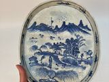 quelqu'un tient une assiette décorée de motifs bleus et blancs