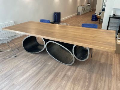 une table en bois sur laquelle sont posés des tuyaux métalliques, au milieu d'une pièce