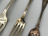 three forks and two spoons sitting on a table