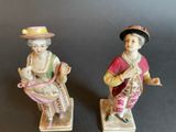 two figurines of a woman and a man sitting on top of each other