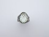 a ring with an oval faceted green amethe surrounded by a filigree band