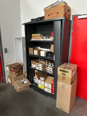 Des cartons, les uns empilés sur les autres, sont rangés sur une étagère dans un local de stockage