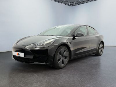 une Tesla Model 3 noire garée dans une pièce blanche