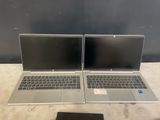 two laptops are sitting on a table with a tablet and a phone