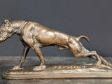 statue en bronze représentant un chien en train de courir, posée sur un socle posé sur une table