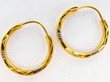 two pairs of gold hoop earrings on a white surface