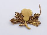 a gold brooch with a leaf and a heart on it