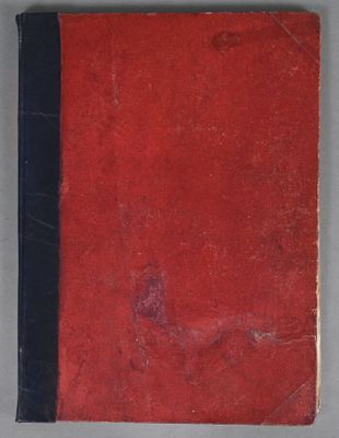 an old book with a red cover sitting on top of a table