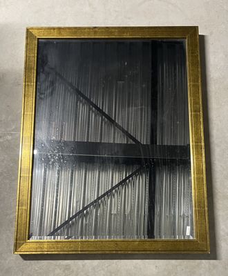 an image of a gold framed mirror hanging on a wall