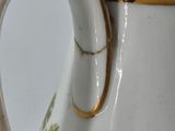 a close up of a white vase with a gold handle