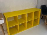 une bibliothèque jaune avec deux chaises noires à côté