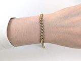 Quelqu'un porte un bracelet en or orné de pierres vertes.