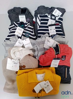 une pile de pulls et un sac à main posés sur une table