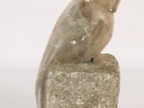 statue of a bird sitting on a rock on a white background