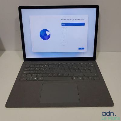 un ordinateur portable ouvert posé sur une table blanche