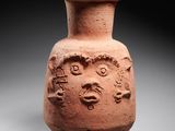 a close up of a clay vase with a face on it