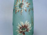 un vase en verre sur lequel sont peintes des fleurs sur un fond blanc