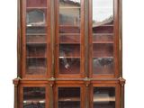 une bibliothèque ancienne en bois, avec des portes vitrées et des étagères