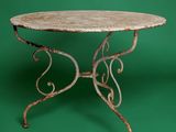 an old iron table with a marble top on a green background