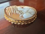 a picture of a gold and white cameo broochle on a table