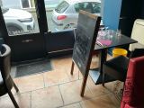 tables and chairs in a restaurant with a chalk board in front of a window