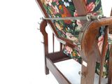 une chaise en bois avec un coussin à motifs floraux sur l'assise et le dossier