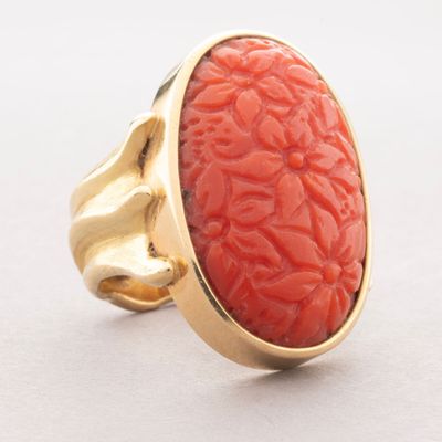 an image of a gold ring with a coral stone in the center