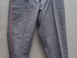un pantalon gris orné de galons rouges, suspendu à un cintre accroché au mur
