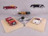 four different model cars are on display on a wooden platform